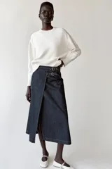 Falda midi de denim azul oscuro, de tiro alto, con diseño cruzado, abertura frontal y ajuste lateral con doble hebilla metálica.