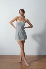Camisón corto gris con textura acanalada, breteles finos y detalles de encaje color crema en escote y ruedo.