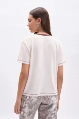 Remera color crudo de manga corta con cuello redondo y ribete marrón. Estampa frontal de Mickey Mouse con texto "Global Explorer Since 1928".