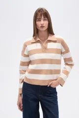 Sweater de tejido de punto, holgado, con rayas horizontales anchas en blanco y negro. Presenta cuello polo con escote en V y mangas largas.