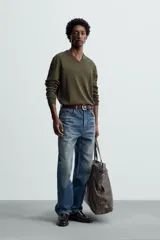 Jersey verde oscuro de punto fino, con cuello en V y mangas largas.