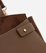 Cartera satchel mediana color marrón, confeccionada en cuero sintético con detalles en gamuza. Cuenta con asas medianas, cierre de cremallera y detalles metálicos dorados. Incluye correa extraíble y regulable.