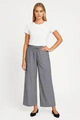 Pantalón de lino color beige, de corte ancho y tiro alto, con bolsillos laterales y cintura elastizada con cordón ajustable.