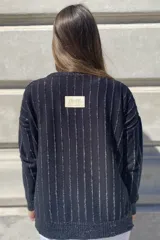 Sweater negro de tejido de punto con escote en V y rayas verticales plateadas.