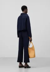 Pantalón tobillero azul marino con textura seersucker de algodón, corte flare, trabillas y cierre lateral con cremallera.