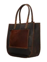 Bolso tipo shopper de piel con pelo en tonos marrones, bordes cosidos a mano con hilo grueso y dos asas de cuero trenzado con flecos largos colgantes.