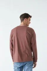 Remera blanca de manga larga con cuello redondo y estampado de un edificio antiguo.