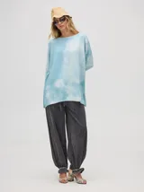 Buzo de algodón con efecto tie-dye en tonos celeste y blanco, de corte holgado y largo por debajo de la cintura, con puños acanalados.