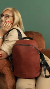 Mochila marrón de símil cuero con cierre principal y bolsillo interno con cierre. Tiene asa de mano, correas regulables y bolsillo oculto en la espalda.