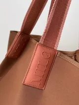 Bolso negro tipo tote de neopreno con bolsillo interno de red, sobre haciendo juego y gancho para sujetarlo.