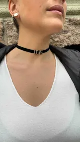 Gargantilla choker de terciopelo negro con letras doradas formando la palabra 'Love'.
