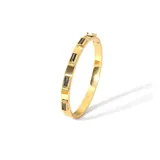 Brazalete rígido dorado con incrustaciones de circonitas rectangulares negras.