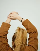 Pulsera de cuero negro con dije central de cristal facetado gris y detalles en metal dorado.