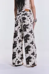 Pantalón de denim de corte wide leg con estampado de manchas de vaca.