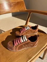 Championes urbanos de cuero color blanco hueso con detalles en marrón. Presentan cordones de algodón color crudo y logo bordado en el lateral.