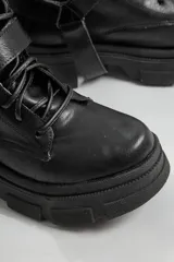 Borcegos negros de ecocuero con cordones y hebilla lateral.
