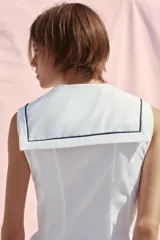 Top blanco de popelina con cuello marinero, escote pico, sin mangas y lazo negro en el frente.