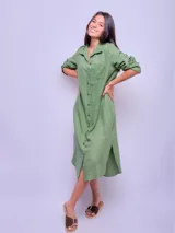 Vestido camisero largo de lino color beige, con cuello clásico, manga larga con puños abotonados y cierre frontal con botones. Tiene un bolsillo de parche en el pecho.