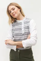 Blusa rosada con mangas largas, cuello con volados y estampado de líneas verticales.