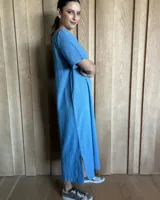Vestido midi negro con cuello redondo y mangas cortas. Presenta dos bolsillos cuadrados en el pecho y ribetes blancos en cuello, mangas, bolsillos y ruedo.