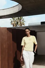 Camiseta blanca de algodón con cuello redondo, manga corta y detalle de flores con volumen a tono en el delantero.