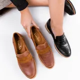 Mocasín de cuero vacuno color marrón, con detalle de antifaz en gamuza. Tiene taco de madera foliado en cuero de 2,5cm y entre suela de goma de 1cm.