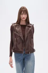 Chaleco estilo biker de eco-cuero color marrón oscuro, con solapas anchas, cierre frontal asimétrico y detalles de tachas plateadas. Presenta cinturón ajustable con hebilla en el ruedo.
