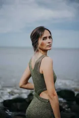 Vestido corto de tejido de punto color verde oliva con lurex dorado, sin mangas y con aberturas laterales en la cintura.