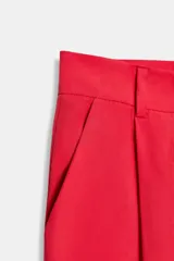 Pantalón negro de tiro alto con corte palazzo, bolsillos laterales y pliegues frontales. Cierre frontal con cremallera y botón.