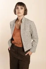Chaqueta de sastrería color crudo con textura tweed, corte entallado, cuello mao y mangas largas.