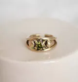 Anillo de bronce con diseño abierto y una zirconia verde engarzada.