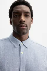 Camisa celeste de corte recto, manga corta y cuello solapa.