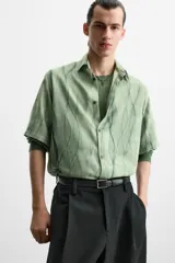 Camisa verde agua con estampado abstracto, corte relaxed fit, cuello solapa, manga corta y cierre frontal con botones.