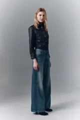 Pantalón de jean denim azul de tiro medio, pierna ancha y lavado con efecto bigotes.