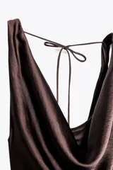 Vestido largo marrón satinado con escote pico fluido y tirantes anchos. Espalda descubierta ajustable con cordones y bajo asimétrico evasé.