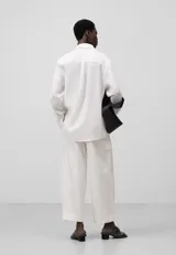 Pantalón cargo de mujer confeccionado en lino y algodón color blanco, de corte recto y tiro alto, con cierre de botón y trabillas. Presenta bolsillos laterales con solapa, bolsillos de vivo en la espalda y logo bordado en la parte trasera.