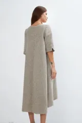 Vestido largo debajo de la rodilla, acampanado, color marrón, con cuello bote, bolsillos laterales y mangas 3/4 con detalle de tajo.