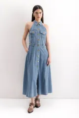 Vestido midi de denim celeste, con cuello camisero halter, botones dorados en el frente, bolsillos en el pecho y falda acampanada.