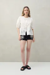 Short de denim negro con bordado floral blanco, bolsillos funcionales y bajo con pequeña abertura lateral.