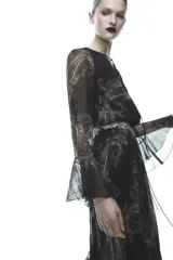 Vestido largo negro con estampado paisley, escote en pico, mangas largas acampanadas con volantes y cintura elastizada con cordón ajustable.
