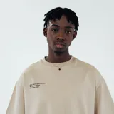 Remera color beige con cuello redondo y estampado con texto en el pecho y logo en la parte inferior.