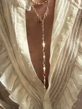 Set de dos collares dorados: uno tipo choker con esferas y otro tipo corbatín con dije de cadena con piedras de colores.