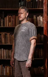 Remera gris con efecto lavado, corte holgado y estampa frontal con una mujer abrazando un leopardo, rodeada por una serpiente y hojas, con la leyenda 'La Fuerza'.