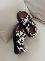 Sandalias con plataforma color marrón y tiras con estampado de vaca en blanco y negro.