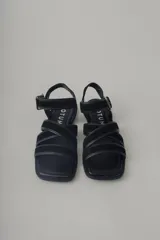 Sandalia plana de cuero color verde militar, con tiras cruzadas en el empeine y una tira ajustable con hebilla metálica dorada en el tobillo.