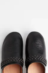 Zueco negro con detalles de tachas en la parte frontal y tacón de madera.