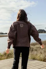 Campera tipo bomber de jean negro con cierre frontal dorado, bolsillos laterales y cuello alto. Tiene mangas largas con puños elastizados y detalles de costuras a contratono en cuello y pretina.