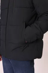 Campera puffer gris con capucha, cierre frontal con cremallera y bolsillos laterales con cierre.