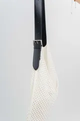 Bolso tejido color crudo con textura calada y correa de eco-cuero negra regulable con hebilla metálica.