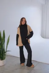 Conjunto de viscosa con felpa, compuesto por un buzo de cuello alto con mangas largas en color negro y paneles laterales en color beige, y un pantalón Oxford negro.